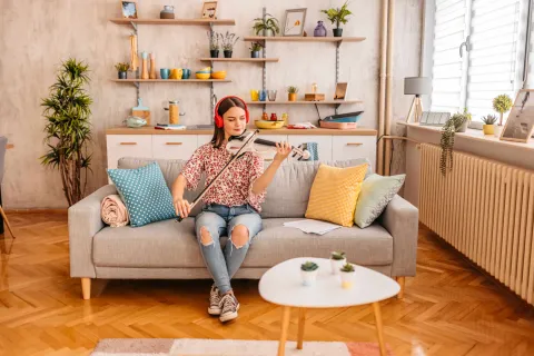 Eine Frau sitzt auf dem Sofa und spielt Geige.