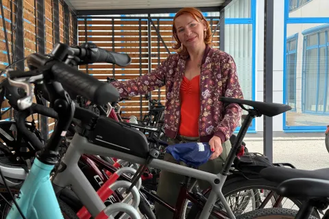 Eine Frau steht lächelnd in einer Reihe von Fahrrädern.