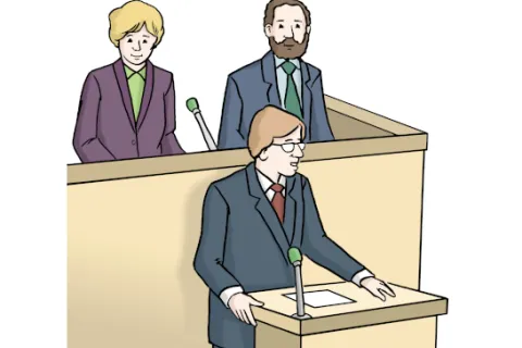 Drei Politiker tragen Anzüge. Einer spricht am Rednerpult mit Mikrofon. Die anderen zwei stehen dahinter mit einem Mikrofon.