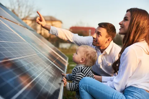 Ein Mann zeigt seiner Familie die Sonnenkollektoren einer Solaranlage.