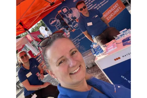 Drei Mitarbeitende der Stadtwerke in einem orangen Pavillon