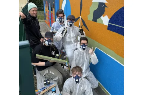 Junge Leute in Schutzkleidung beim Arbeiten mit Graffiti