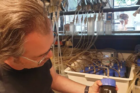 Mann mit Versuchsbehälter in der Hand