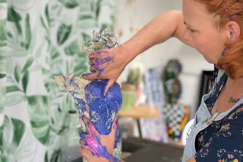 Eine Frau moduliert eine Figur aus Papier und Draht.