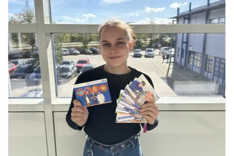 Junge Frau vor einem Fenster mit Postkarten in der Hand