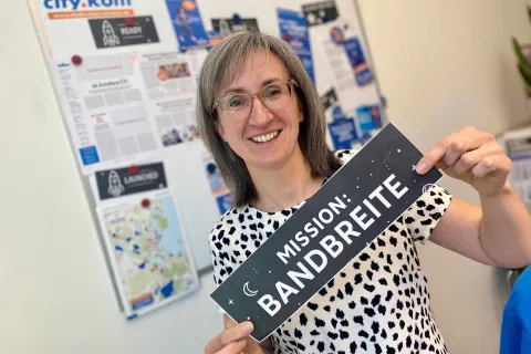 Frau im Büro mit Schild "Mission Bandbreite"