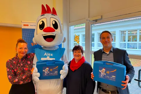 Drei Personen stehen mit dem Stadtwerkemaskottchen zusammen