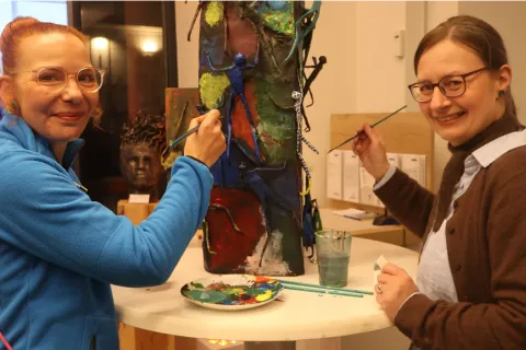 Zwei Frauen gestalten eine Skulptur mit Farbe.