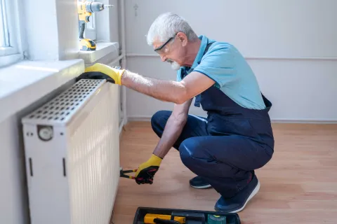 Ein Handwerker wartet eine Heizung, um Energie zu sparen.