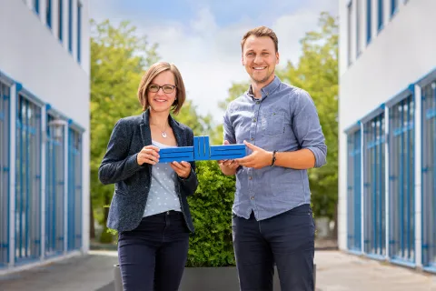 Eine junge Frau und ein junger Mann halten zusammen das blaue Logo der Stadtwerke Schwerin