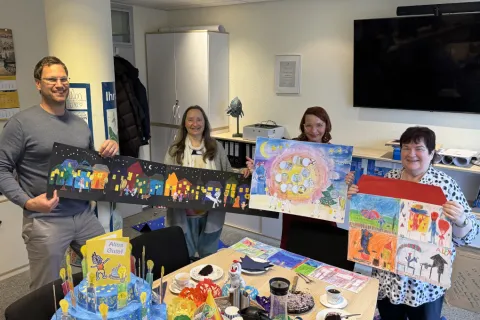 Ein Mann und drei Frauen präsentieren die Werke einer Malaktion für Kinder