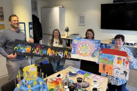 Ein Mann und drei Frauen präsentieren Werke einer Malaktion für Kinder