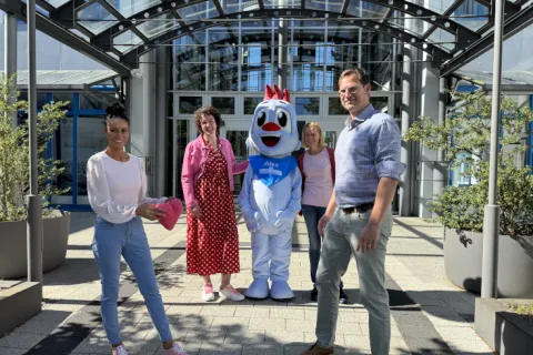 Eine junge Frau übergibt ein rosa Plüschherz an einen Mann