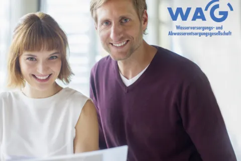 Ein Mann und eine Frau im Büro lächeln in die Kamera