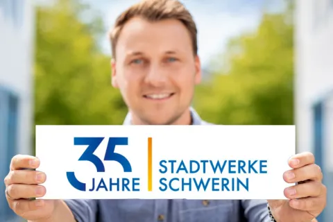 Mann hält vor sich ein Schild mit dem Emblem zu 35 Jahre Stadtwerke Schwerin
