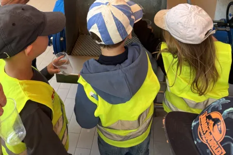 Drei Kinder probieren Trinkwasser