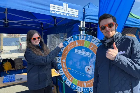 Zwei Auszubildende der Stadtwerke Schwerin stehen vor einem blauen Pavillon.