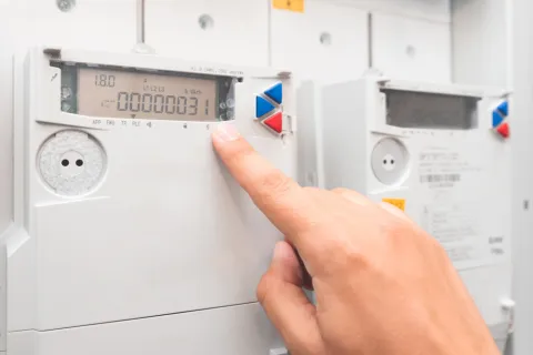 Eine Person liest den Zählerstand vom Display eines digitalen Zählers ab