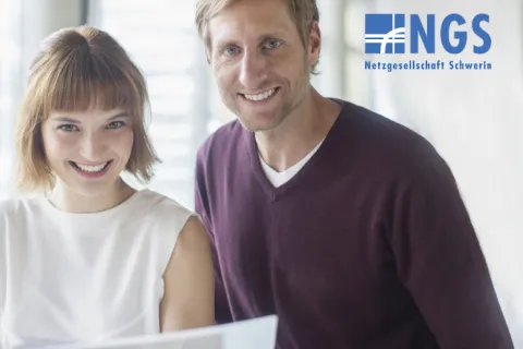 Ein Mann und eine Frau im Büro lächeln in die Kamera