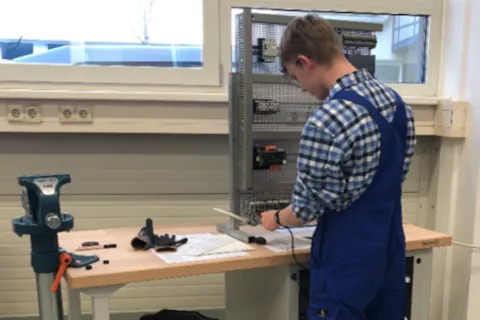 ein gewerblicher Auszubildender arbeitet am Schaltschrank