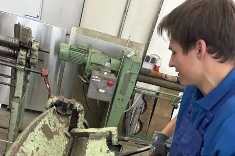 Ein gewerblicher Azubi arbeitet an einer Maschine