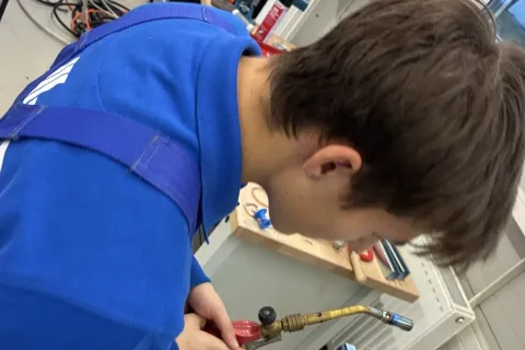 Ein gewerblicher Azubi arbeitet mit einem Bunsenbrenner