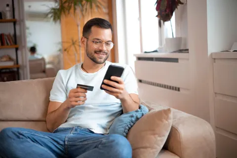 Ein Mann gibt Daten seiner Bankkarte auf seinem Handy ein