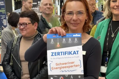 Eine Mitarbeiterin der Stadtwerke hält ein Zertifikat in die Kamera