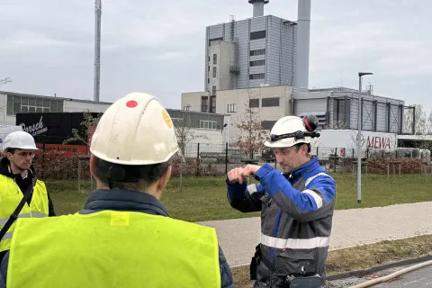 Ein Stadtwerkemitarbeiter mit typischer Arbeitsbekleidung erklärt Besuchenden etwas.