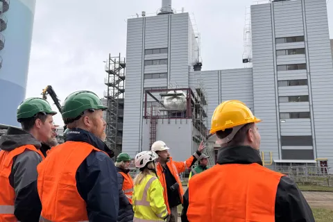 Eine Besuchergruppe steht vor dem charakteristischen Heizkraftwerk in Schwerin Süd.