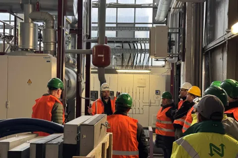 Ein Stadtwerkemitarbeiter mit typischer Arbeitsbekleidung steht im Heizkraftwerk und gibt Auskunft bei einer Führung.