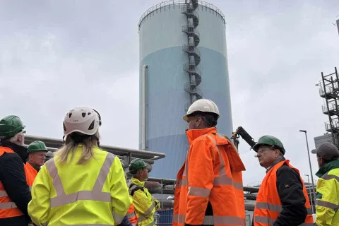 Eine Besuchergruppe steht vor dem zylindrischen Wärmespeicherturm.