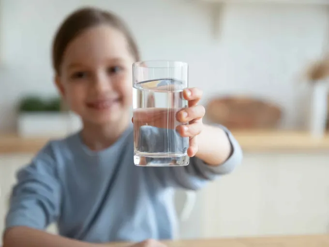 Kind freut sich über ein Glas Wasser.