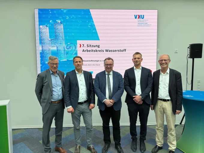Vertreter aus Politik und Wirtschaft in MV stehen vor dem Screen zur 7. Sitzung des Arbeitskreises Wasserstoff.