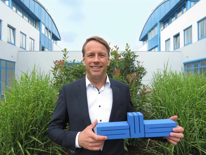 Hanno Nispel hält das Stadtwerke-Logo in der Hand. Im Hintergrund ist der Innenhof des Stadtwerke-Standortes zu sehen.