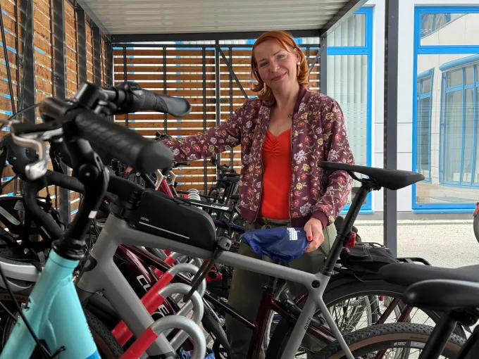 Eine Frau steht lächelnd in einer Reihe von Fahrrädern