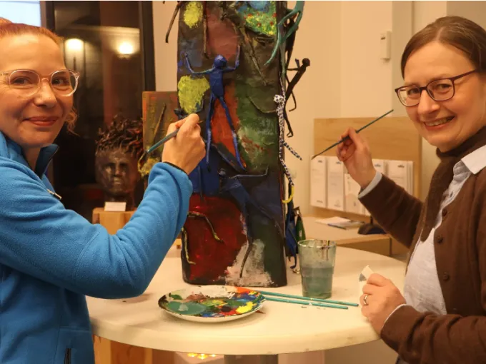 Zwei Frauen gestalten eine Skulptur mit Farbe.
