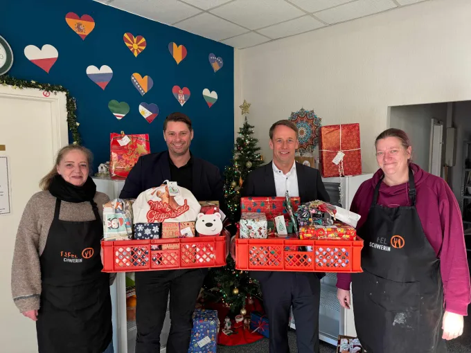 Vier Personen stehen mit bunt verpackten Weihnachtsgeschenken im Speiseraum der Kindertafel Schwerin