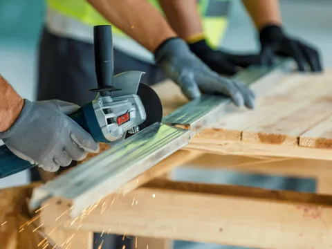 Bauarbeiter schneiden mit der Flex Trockenbauständer.