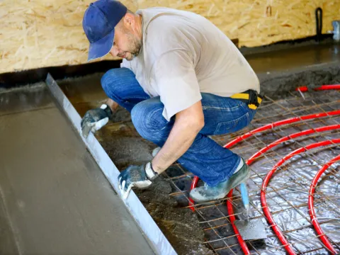 Ein Bauarbeiter zieht Estrich glatt.