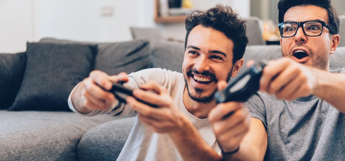 Zwei junge Männer spielen Videospiele und haben viel Spaß.