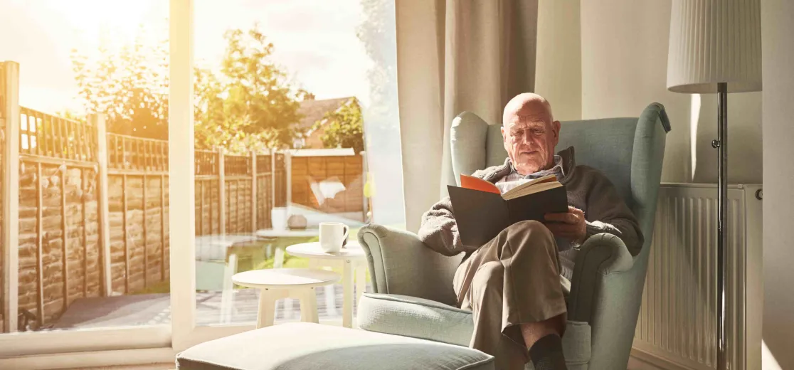 Ein Mann liest ein Buch und hat es gemütlich warm Zuhause.