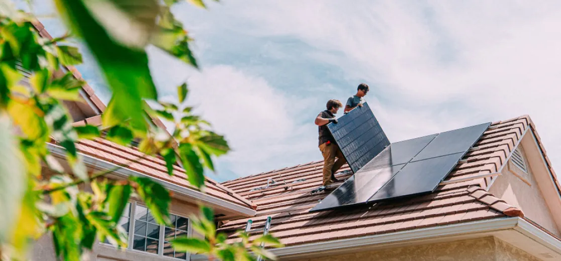 Zwei Männer installieren Solarmodule auf einem Dach.