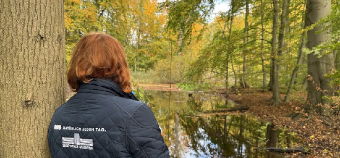 Stadtwerke Mitarbeiterin lehnt sich an einen Baum