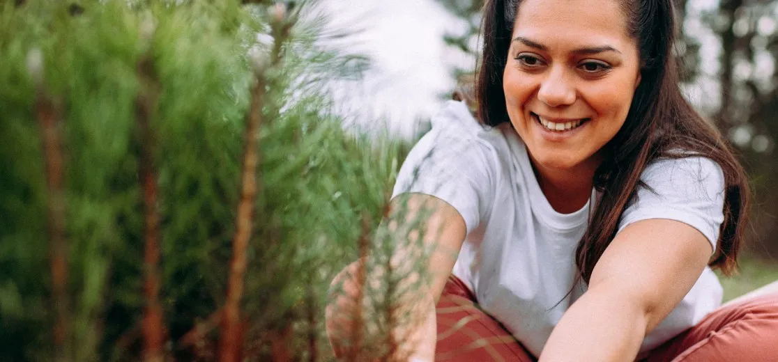 Eine junge Frau pflanzt einen Baum im Wald.