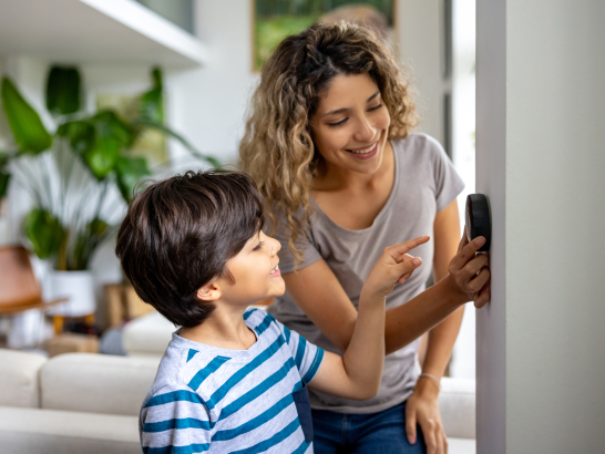 Mutter und Sohn stellen ein Heizungs-Thermostat ein.