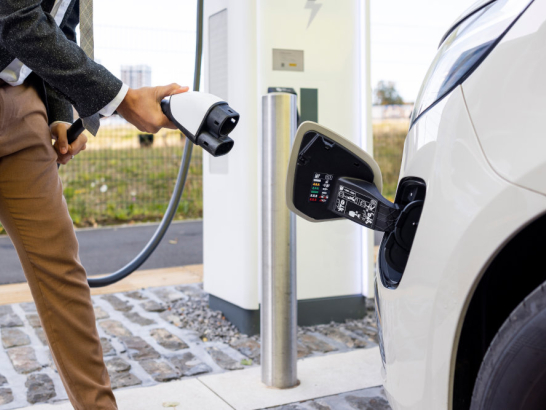 Mann schließt Elektroauto an eine öffentliche Ladesäule an.