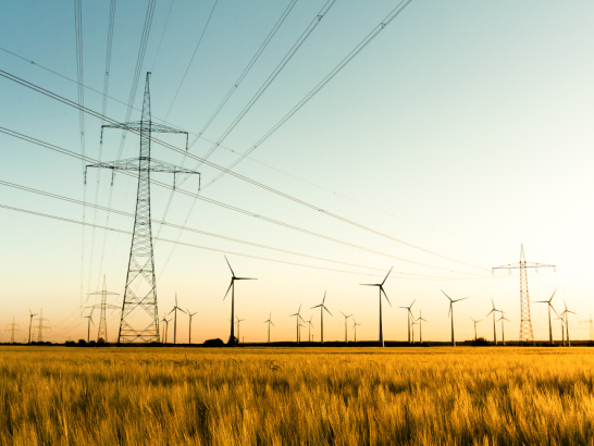 Strommasten und Windräder auf einem Feld.