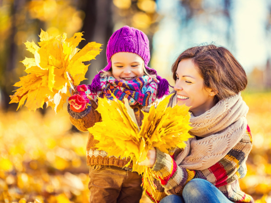 Mutter und Tochter spielen im Herbstlaub