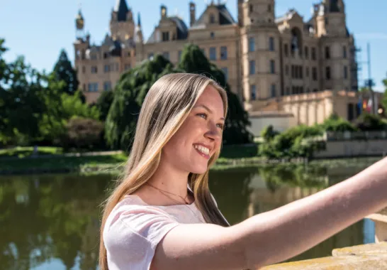 Eine Frau nimmt ein Selfie vor dem Schweriner Schloss von sich auf.